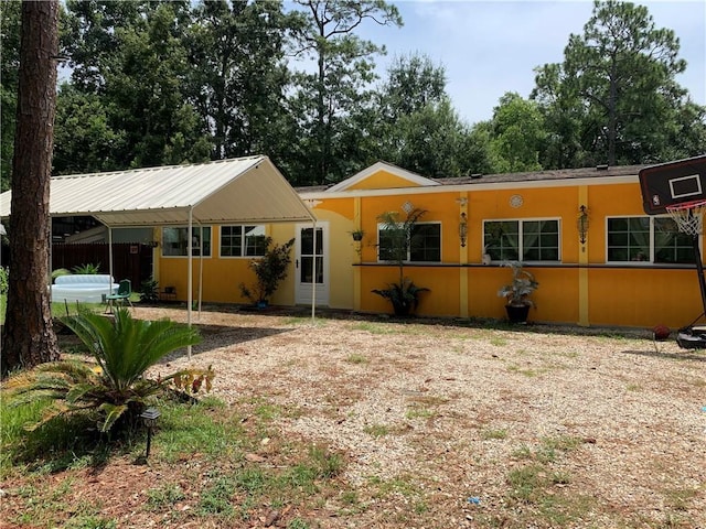 ranch-style house featuring metal roof and stucco siding