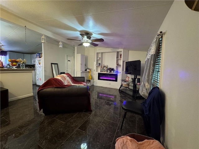 living area with a ceiling fan, a textured ceiling, and baseboards