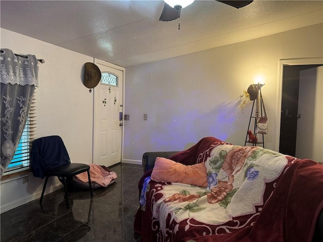 living area with lofted ceiling, ceiling fan, a textured ceiling, and baseboards