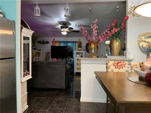 kitchen with a peninsula, ceiling fan, and freestanding refrigerator