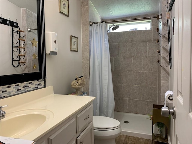 full bathroom featuring toilet, a textured ceiling, vanity, a shower stall, and backsplash