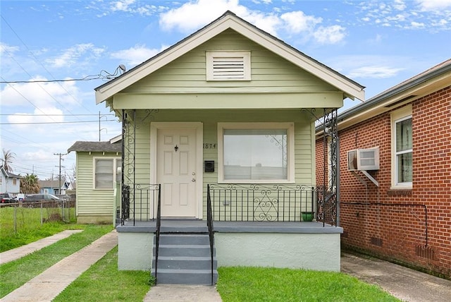 bungalow-style house with a wall unit AC and a porch