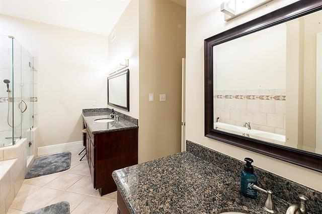 full bath featuring two vanities, a sink, a shower stall, tile patterned flooring, and a bath
