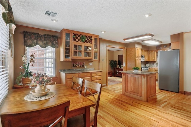 kitchen with stainless steel appliances, a center island, a textured ceiling, and light wood-type flooring