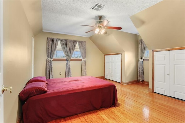 bedroom featuring hardwood / wood-style flooring, ceiling fan, vaulted ceiling, and a textured ceiling