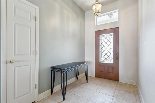 entryway with a chandelier, baseboards, and light tile patterned floors