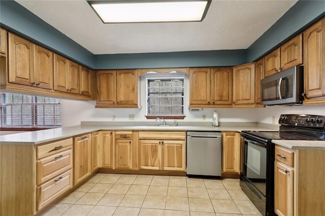 kitchen with stainless steel appliances, kitchen peninsula, sink, and light tile patterned floors