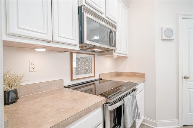 kitchen featuring white cabinets, baseboards, stainless steel appliances, and light countertops