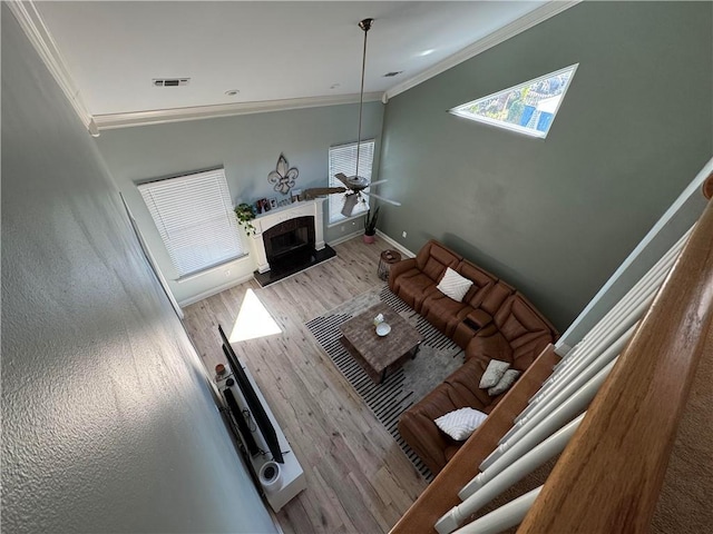 living room with hardwood / wood-style flooring, ornamental molding, a premium fireplace, and ceiling fan