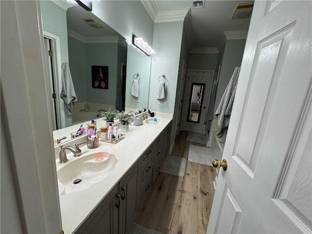 bathroom with vanity, hardwood / wood-style flooring, ornamental molding, and a bathing tub