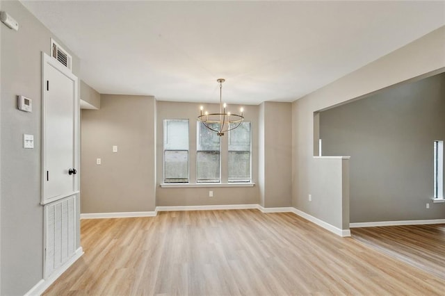 unfurnished dining area featuring plenty of natural light, an inviting chandelier, and light hardwood / wood-style flooring