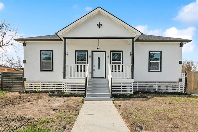 bungalow featuring covered porch, roof with shingles, and fence