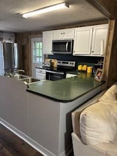 kitchen featuring dark countertops, white cabinetry, stainless steel appliances, and dark wood finished floors