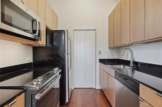 kitchen with stainless steel appliances, sink, light brown cabinets, and dark hardwood / wood-style flooring