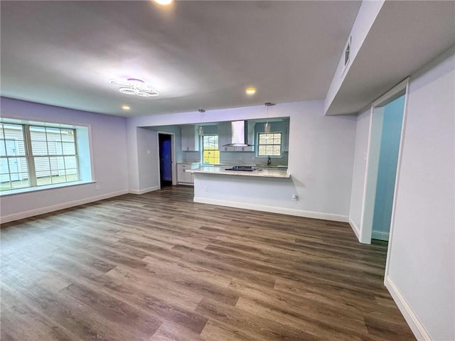 unfurnished living room featuring a healthy amount of sunlight, baseboards, and dark wood-type flooring