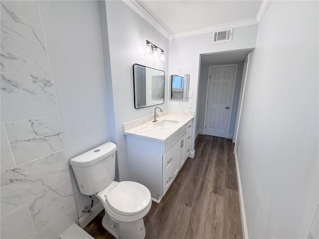 bathroom with visible vents, toilet, ornamental molding, wood finished floors, and vanity