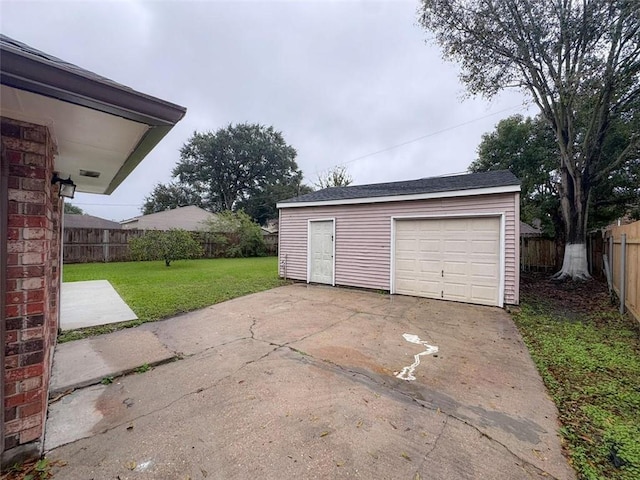 detached garage featuring fence and concrete driveway