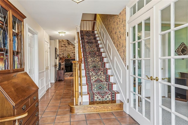 staircase featuring tile patterned flooring, a brick fireplace, and french doors