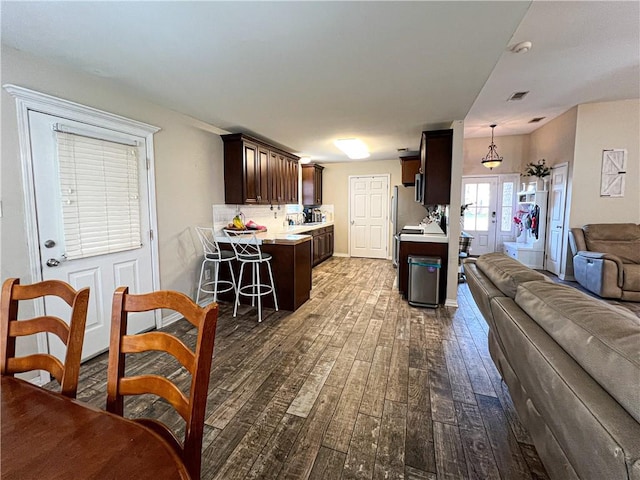 kitchen with french doors, dark brown cabinetry, a breakfast bar, decorative light fixtures, and dark hardwood / wood-style floors