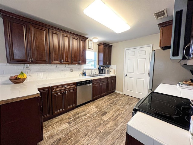 kitchen with stainless steel appliances, light wood-type flooring, backsplash, and dark brown cabinetry