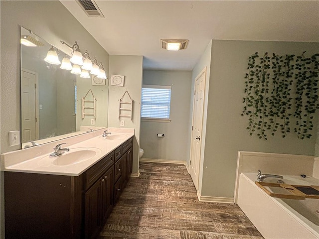 bathroom with a bath, vanity, hardwood / wood-style floors, and toilet