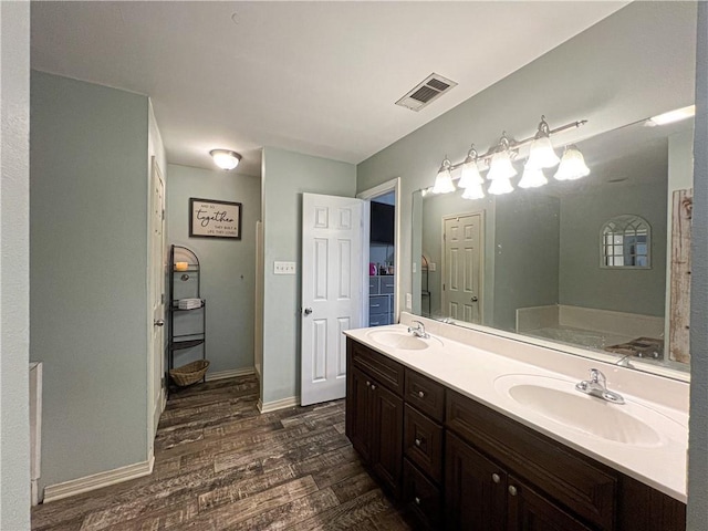 bathroom featuring vanity, hardwood / wood-style floors, and a tub to relax in