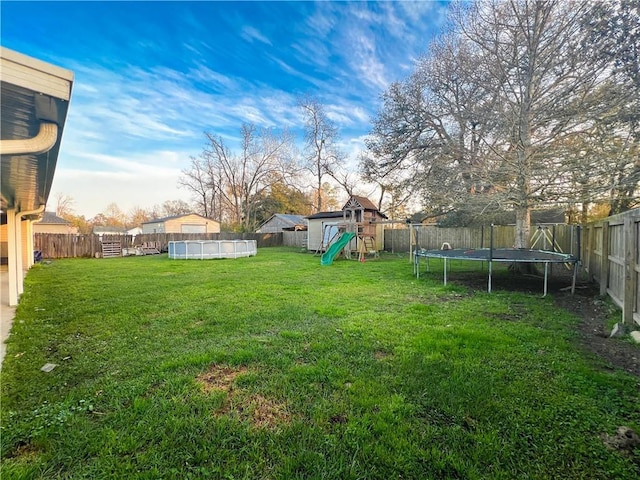 view of yard featuring a trampoline, a swimming pool, and a playground