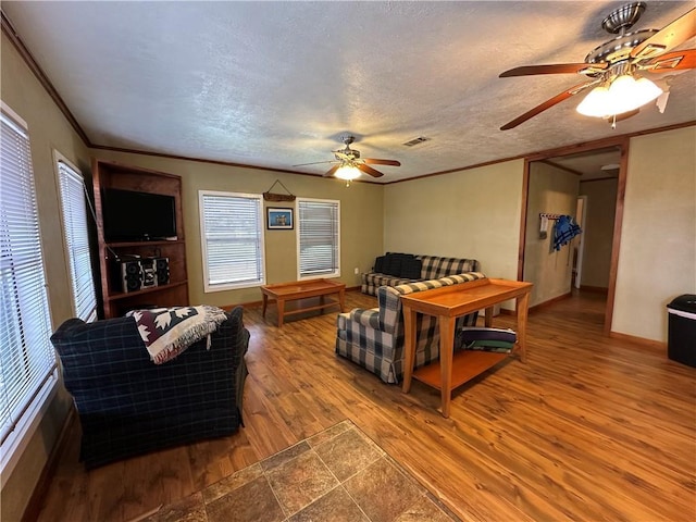 living room featuring hardwood / wood-style floors, ornamental molding, and a textured ceiling