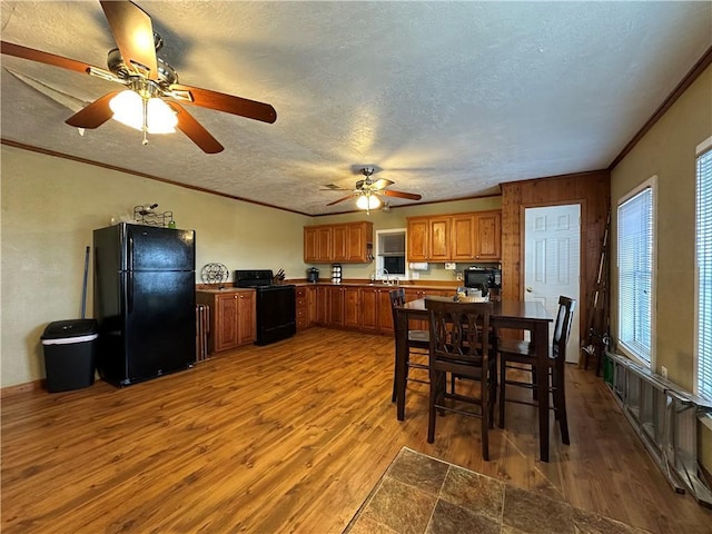 interior space featuring crown molding, black appliances, a textured ceiling, and light wood-type flooring