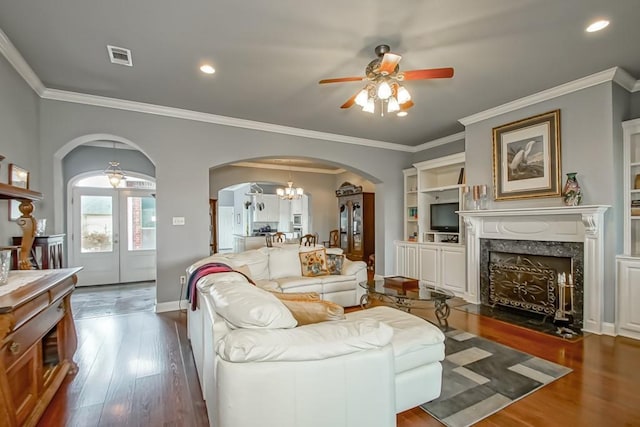 living room featuring dark hardwood / wood-style flooring, ornamental molding, ceiling fan with notable chandelier, and a fireplace