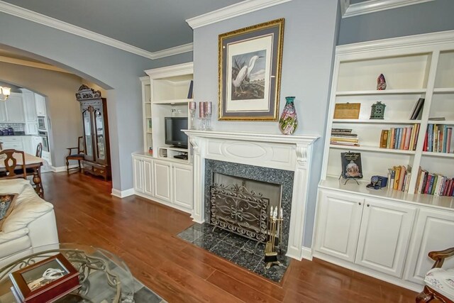 interior space with crown molding, dark wood-type flooring, built in features, and a high end fireplace