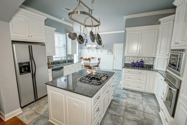 kitchen with white cabinetry, stainless steel appliances, crown molding, and a center island