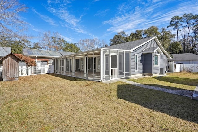 rear view of property with central AC, a lawn, a fenced backyard, and a sunroom