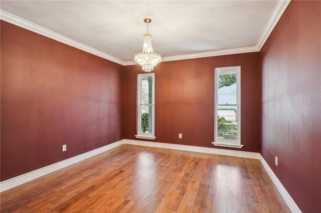 spare room featuring a chandelier, crown molding, hardwood / wood-style flooring, and baseboards