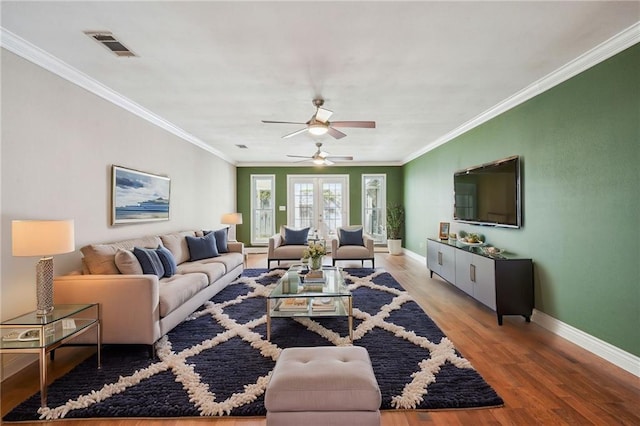 living area with ornamental molding, visible vents, baseboards, and wood finished floors