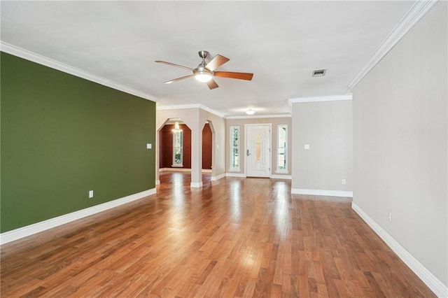 unfurnished living room featuring arched walkways, ceiling fan, light wood finished floors, and baseboards