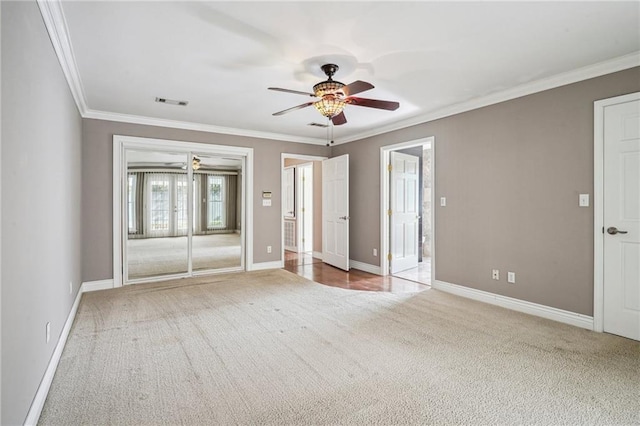 carpeted spare room featuring baseboards, ceiling fan, and crown molding