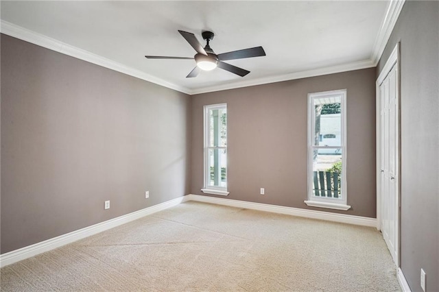 spare room featuring light carpet, ceiling fan, baseboards, and ornamental molding