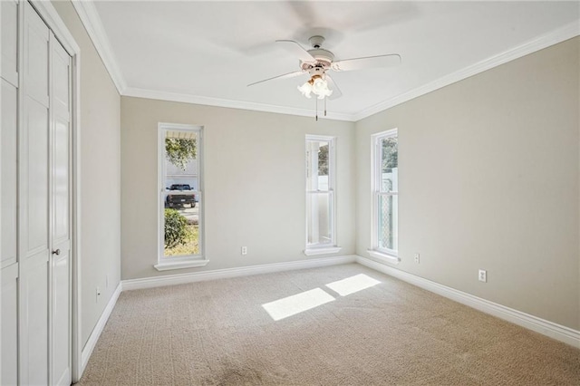 interior space with light carpet, ceiling fan, baseboards, and crown molding