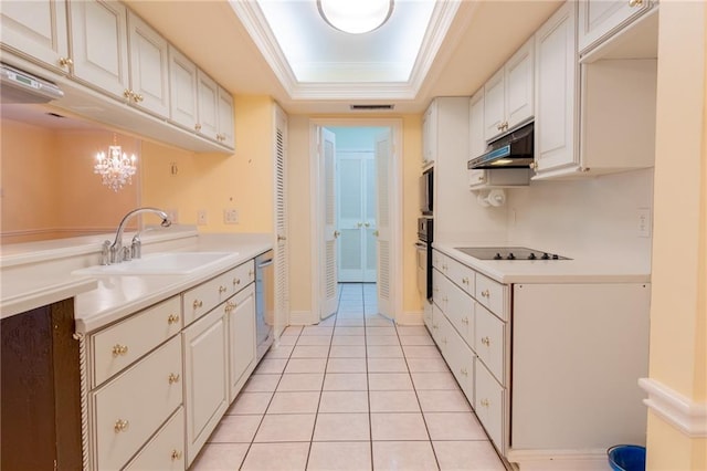 kitchen with hanging light fixtures, a raised ceiling, sink, and white cabinets