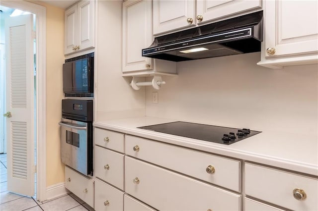 kitchen with white cabinetry, light tile patterned floors, and black appliances