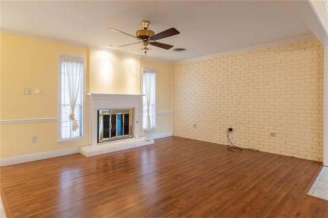 unfurnished living room with ornamental molding, brick wall, dark hardwood / wood-style flooring, and a wealth of natural light