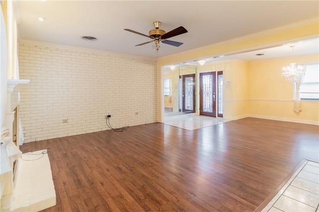 unfurnished living room with hardwood / wood-style flooring, ornamental molding, brick wall, and ceiling fan with notable chandelier