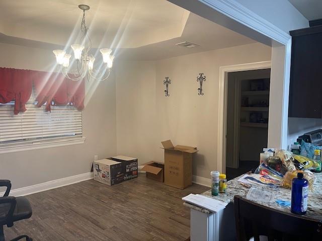 interior space featuring dark wood-type flooring, a raised ceiling, and an inviting chandelier