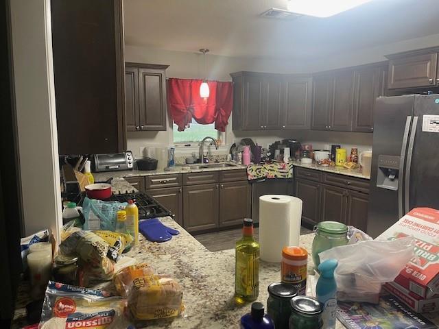 kitchen with sink, dark brown cabinetry, and stainless steel fridge with ice dispenser