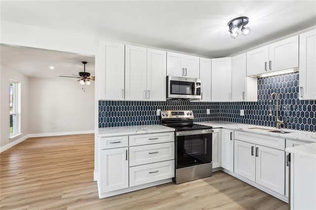 kitchen with appliances with stainless steel finishes, decorative backsplash, sink, and white cabinets