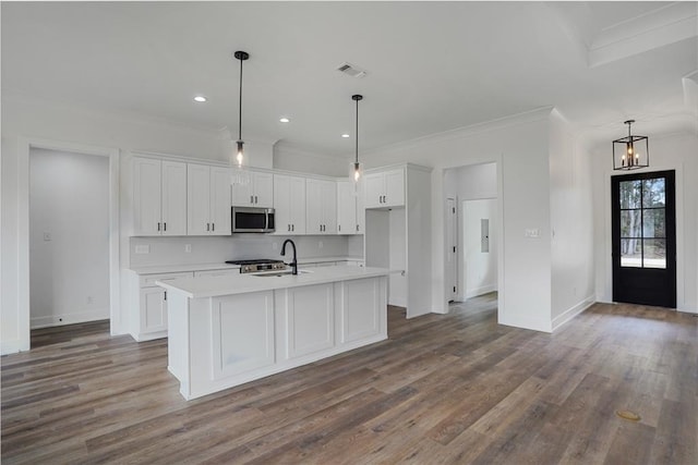 kitchen with sink, crown molding, hanging light fixtures, white cabinets, and a center island with sink