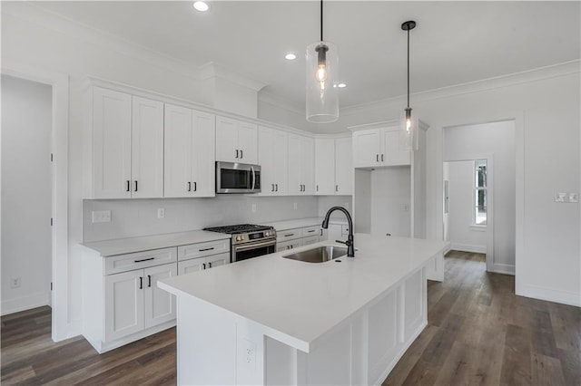 kitchen with an island with sink, white cabinetry, sink, hanging light fixtures, and stainless steel appliances