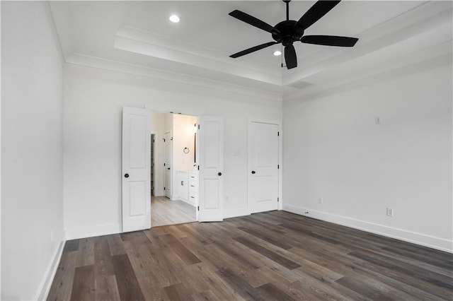 unfurnished bedroom featuring crown molding, ensuite bath, a tray ceiling, and hardwood / wood-style floors