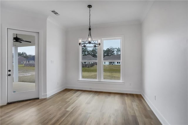 unfurnished dining area with crown molding, an inviting chandelier, and light wood-type flooring